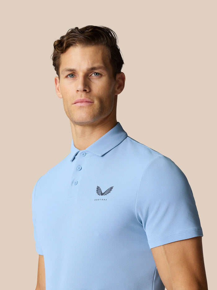 Male model wearing light blue Golf Club Essential Polo with polo collar and logo on chest