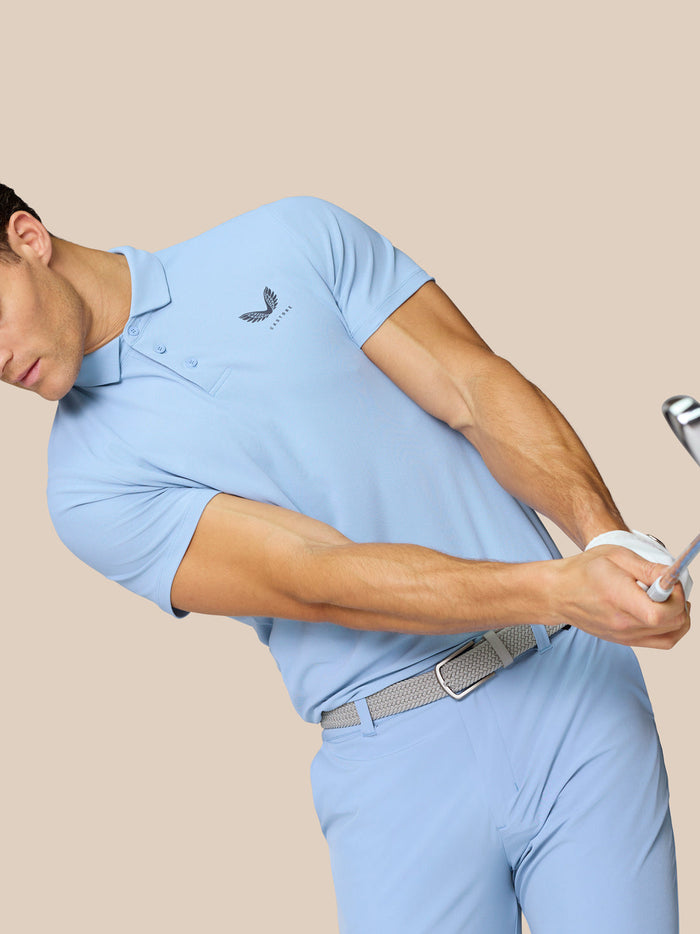 Rear view of a man wearing a sky blue golf polo and shorts with subtle Castore branding along the upper back.
