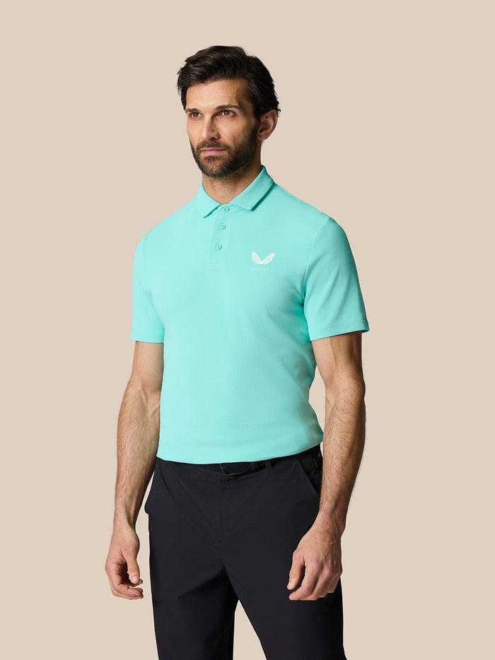 Male model in light aqua Golf Club Essential Polo with dark trousers, front view.