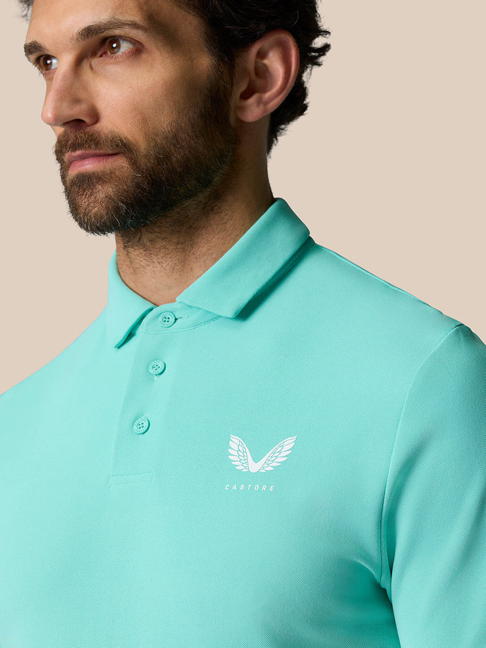 Close-up of a man wearing light aqua Golf Club Essential Polo with a pointed collar and Castore logo on the chest.