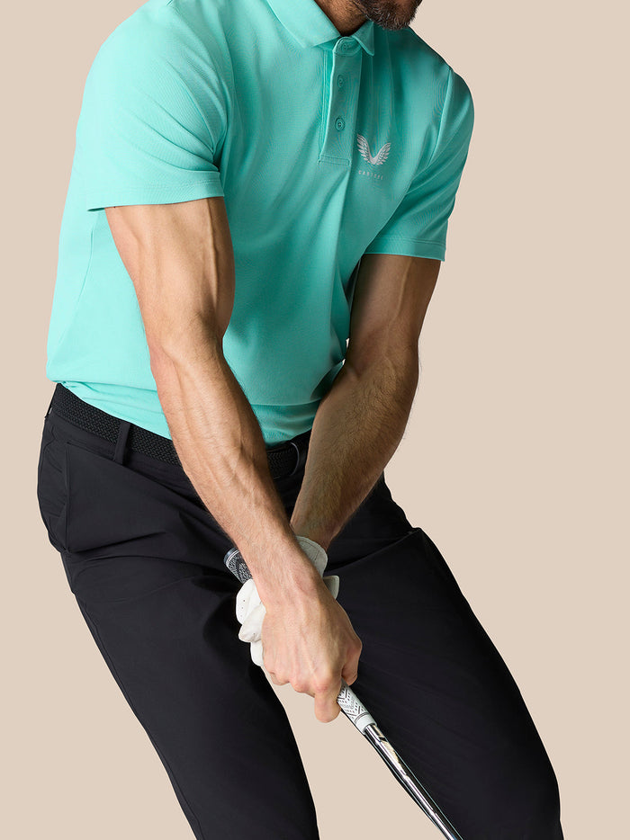 Rear view of a man in a light aqua Golf Club Essential Polo displaying Castore branding on the upper back.