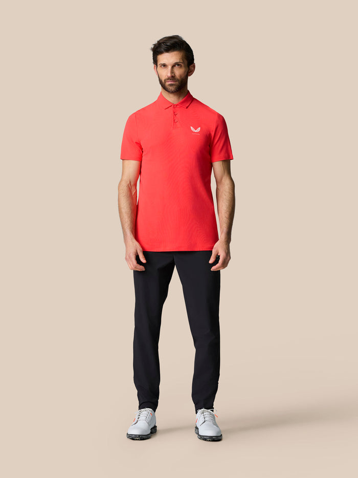 Close-up of red golf polo fabric at the hem with a small vent and Aertek branding.