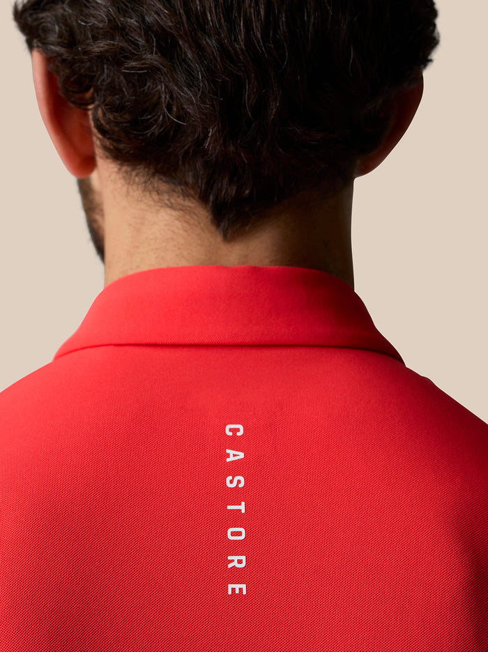 Back view of a man in a red Golf Club Essential Polo showing CASTORE branding along the back.