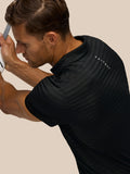 Close up of a man wearing the black Pinnacle Polo with striped knit and Castore branding along the back.