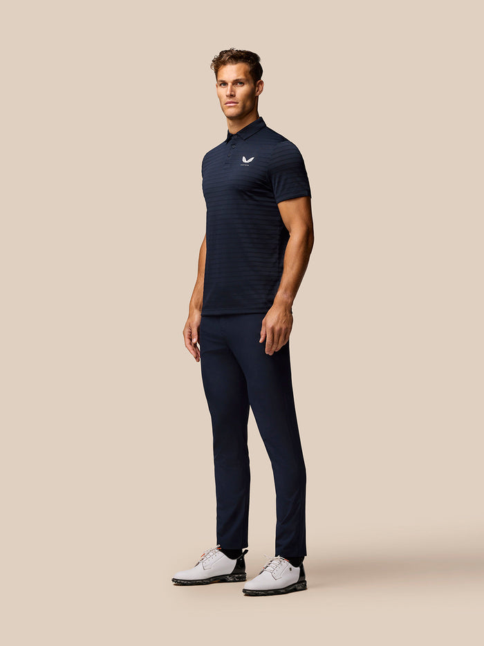 Male model wearing navy Golf Pinnacle Pique Stripe Polo with subtle horizontal stripes and Castore logo on the left chest