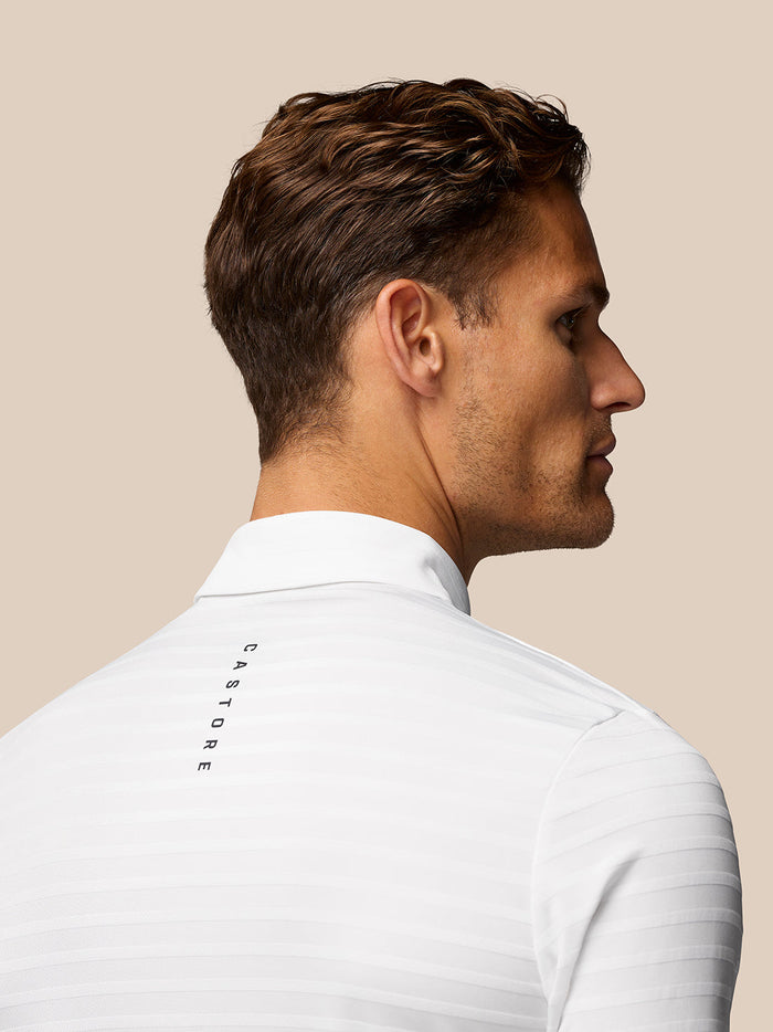 Male model wearing white textured pique stripe polo with short sleeves and stand collar, full body shot