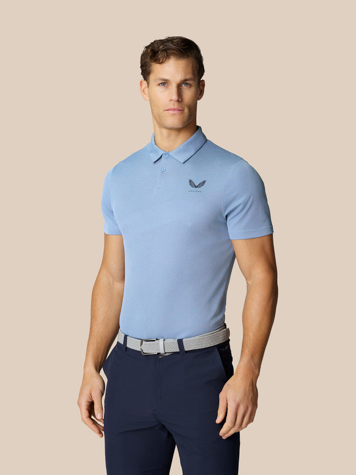 Male model wearing a sky blue breathable polo on a beige studio backdrop