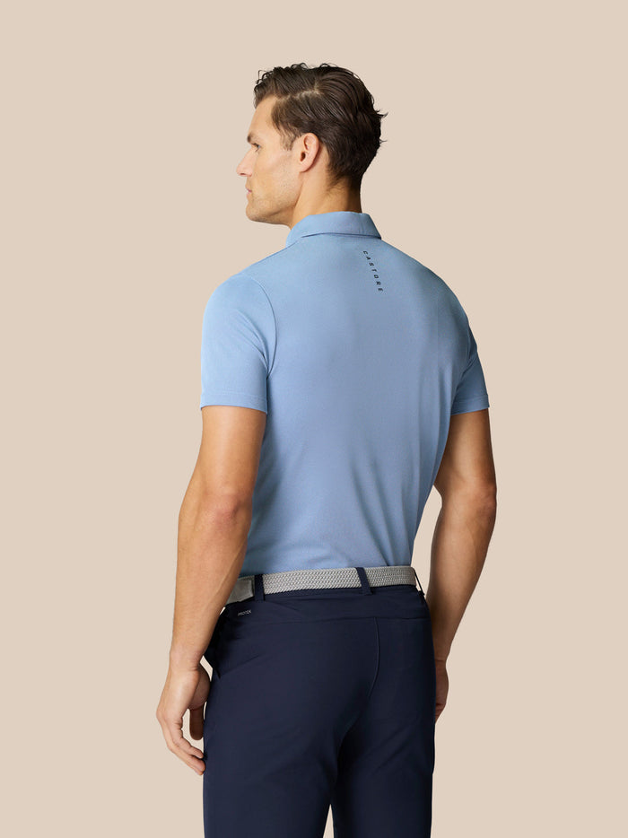 Back view of man wearing a sky blue polo displaying Castore branding along the upper back