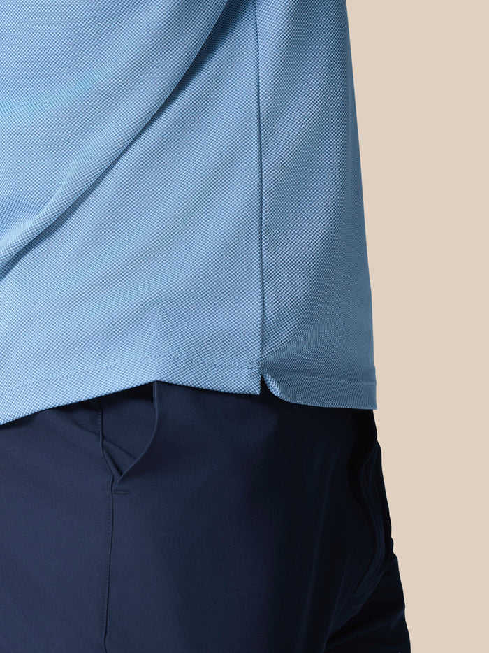 Close-up of light blue textured knit fabric with side hem vent from Golf Pinnacle Polo.