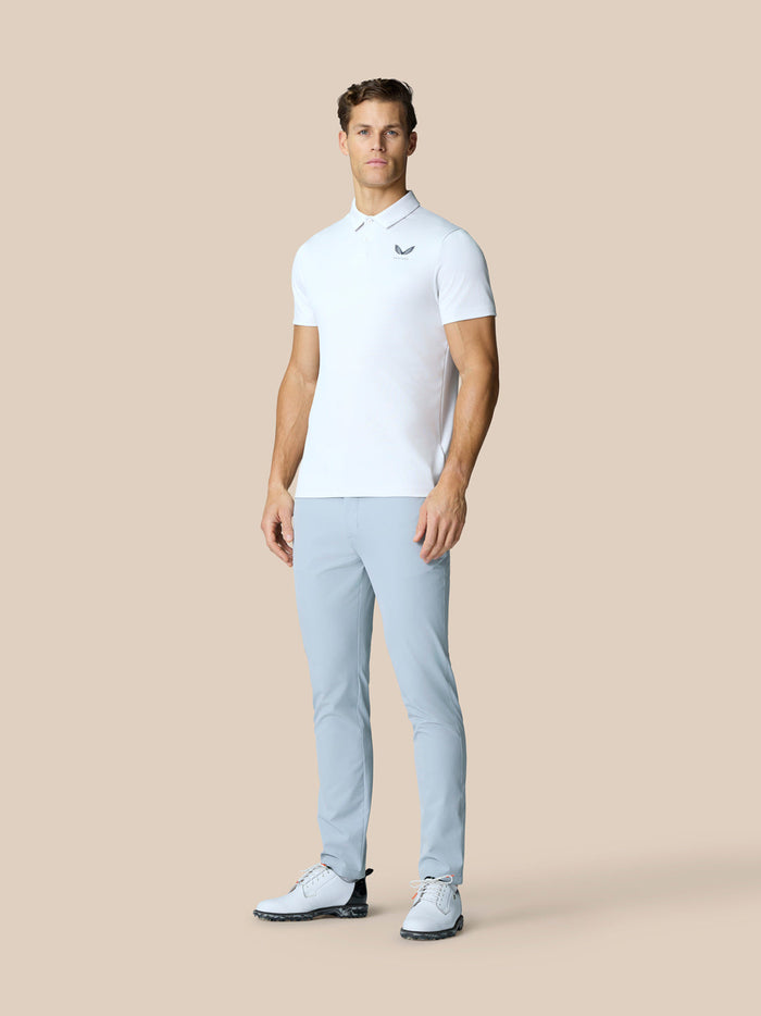 Full body shot of a man in a white Engineered Knit Polo and light blue pants with golf shoes