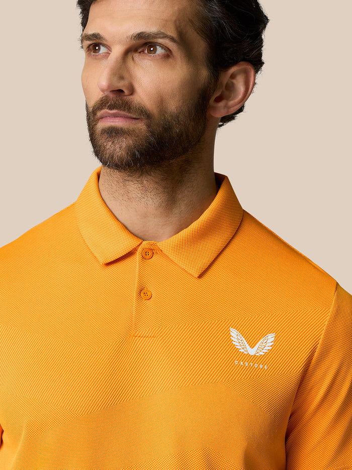 Close up of the orange polo collar with two button placket and a white Castore crest on the left chest.