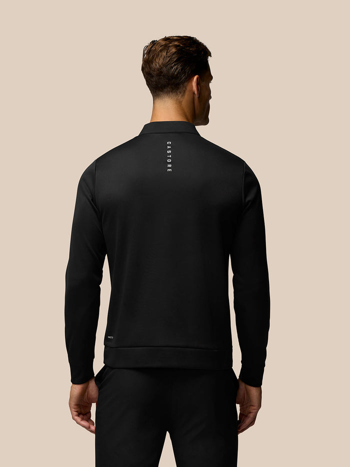 Back view of a black long sleeve golf top with vertical Castore branding centered on the upper back.