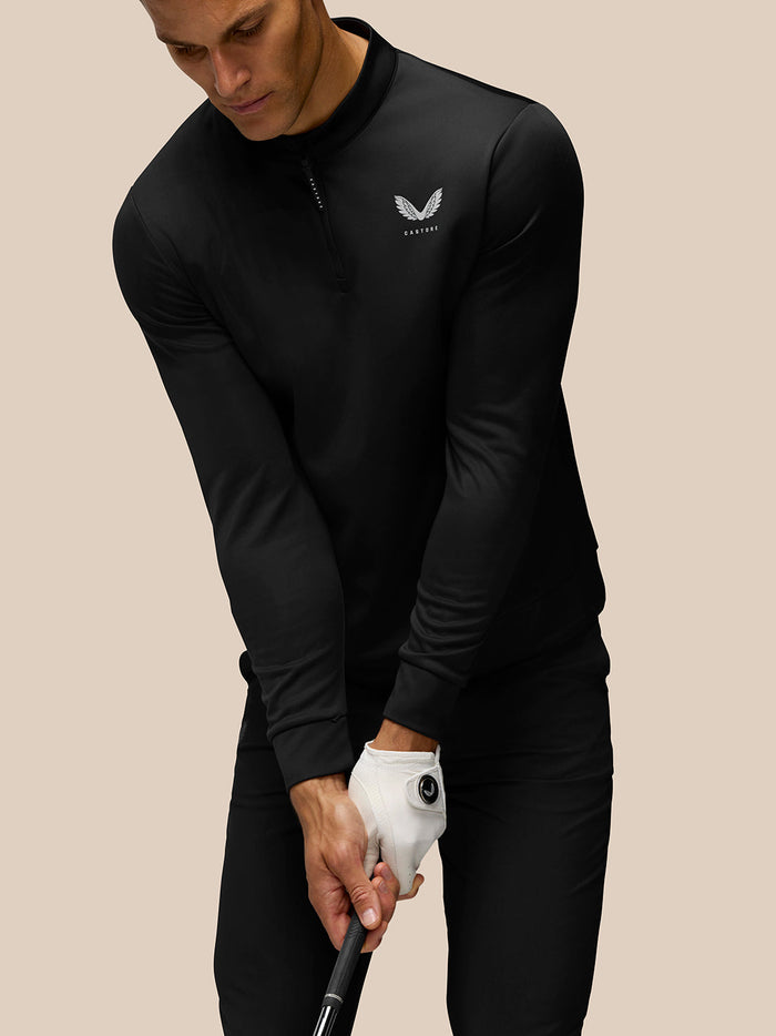 Close-up of a model in the black Golf Club Classic 1/4 Zip Top highlighting the Castore logo on the left chest and upper back