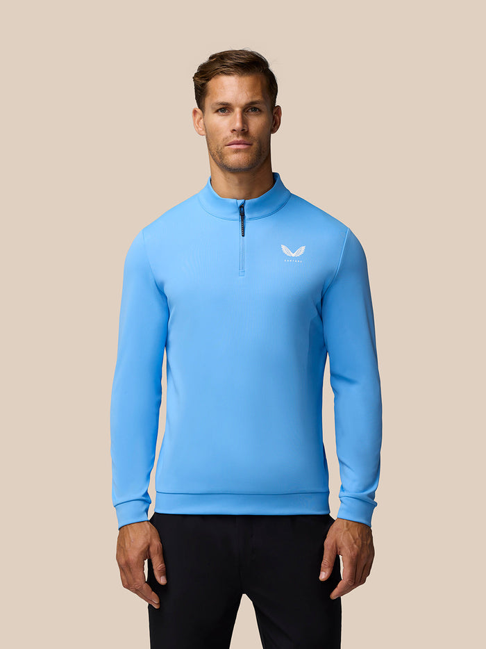 Model wearing cool blue Golf Club Classic 1/4 Zip Top with funnel collar and chest logo.