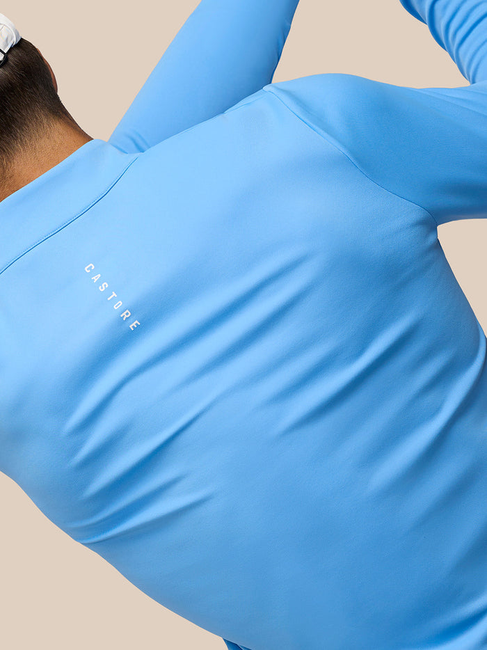 Back view of model wearing Golf Club Classic 1/4 Zip Top in cool blue with white cap; Castore logo visible on back.