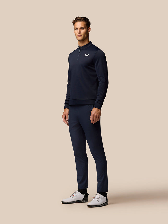Male model wearing Golf Club Classic 1/4 Zip Top in Midnight Navy with stand collar on a beige backdrop