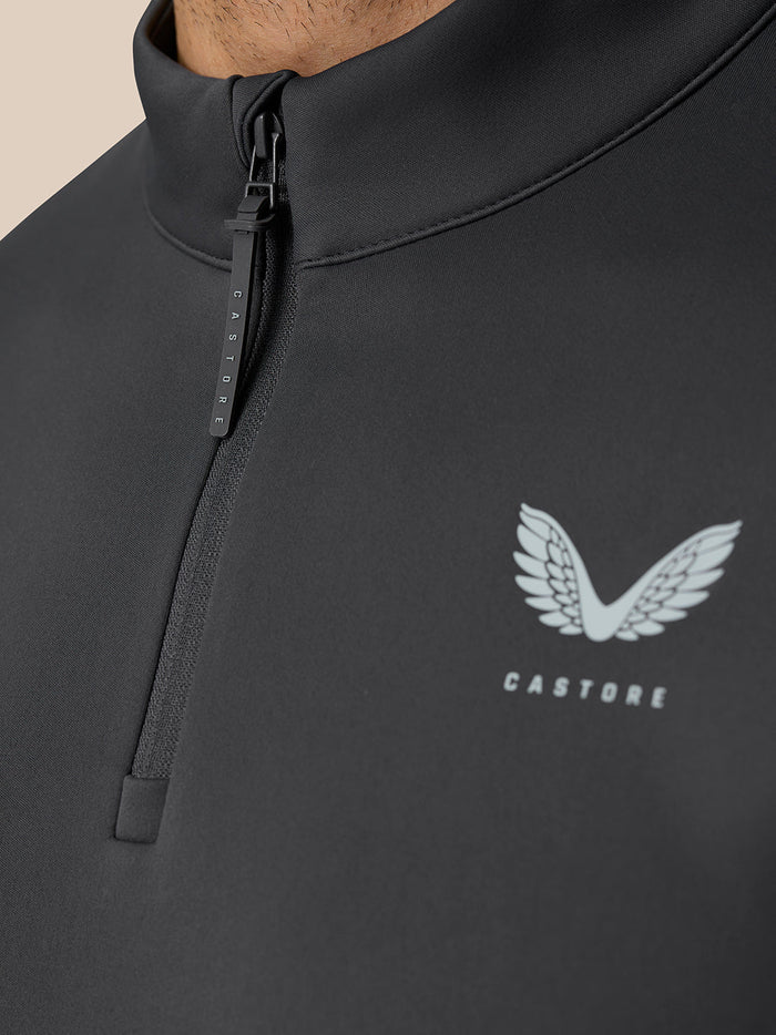 Close-up of the front zipper on the gunmetal Golf Club Classic Quarter Zip Top with Castore logo and wing emblem on the chest.