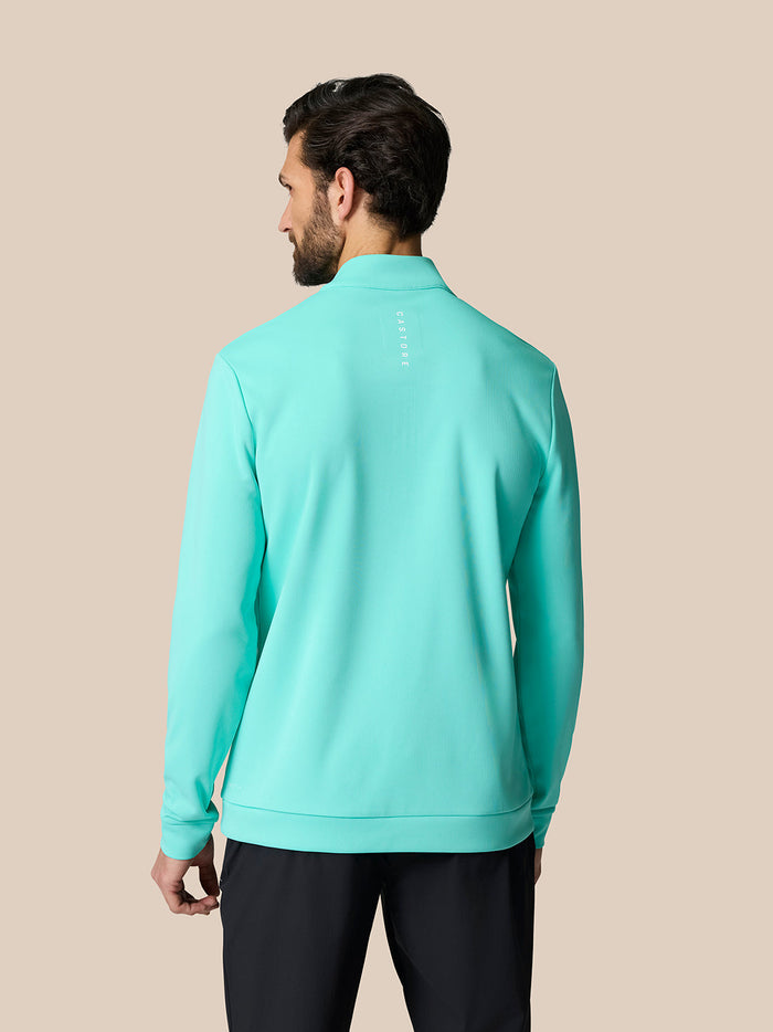 Back view of male model wearing light aqua Golf Club Classic Quarter Zip Top with Castore branding on the upper back.