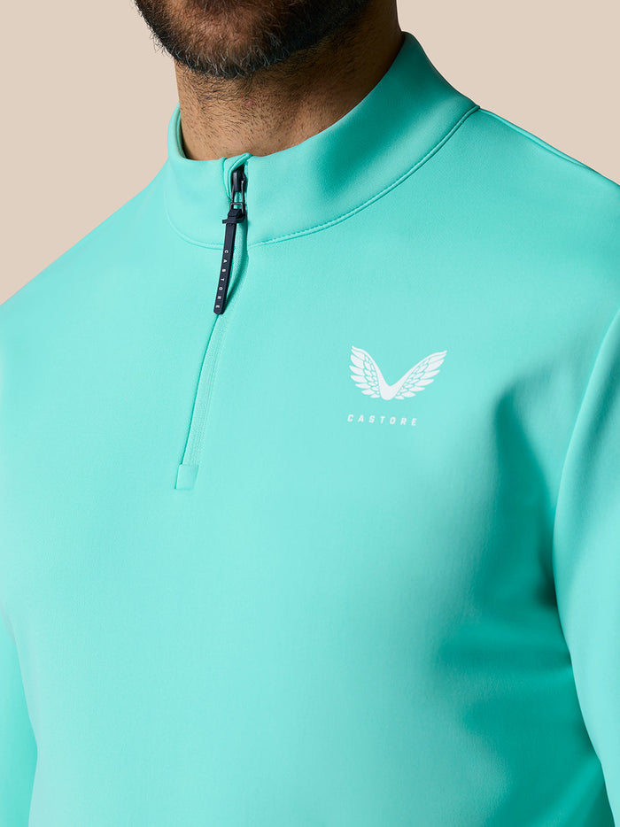 Close-up of light aqua Golf Club Classic Quarter Zip Top showing front zipper and Castore logo on left chest.