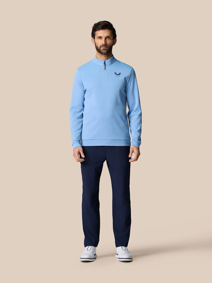 Man in sky blue Golf Club Classic Quarter Zip Top with stand collar and front ¼ zip, paired with navy pants.