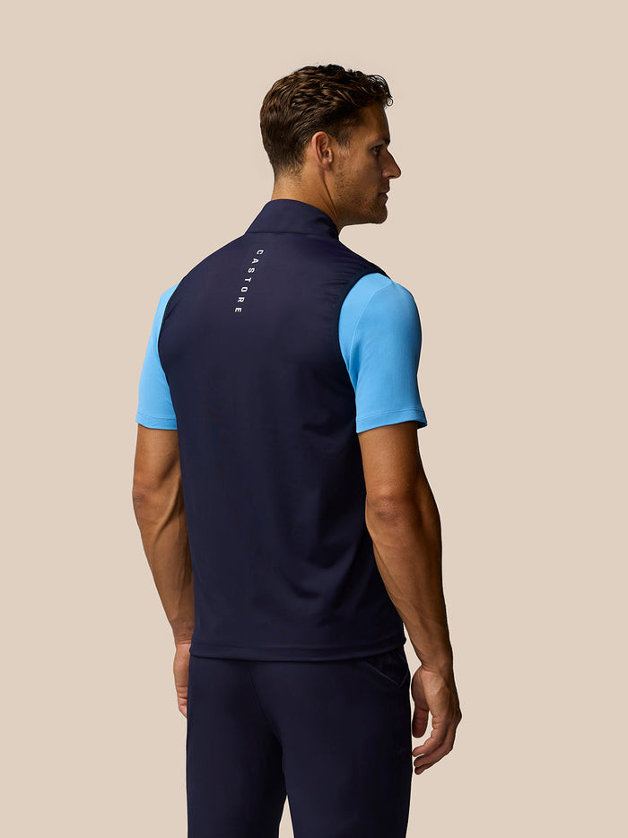Male model seen from the back in navy Pinnacle gilet with Castore branding on the collar and upper back
