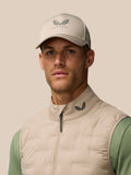 Model wearing beige Pinnacle lightweight hybrid gilet over sage-green top with cap.