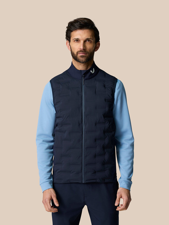 Male model wearing navy Pinnacle Golf Gilet with stand collar and full front zip over a light blue long sleeve top