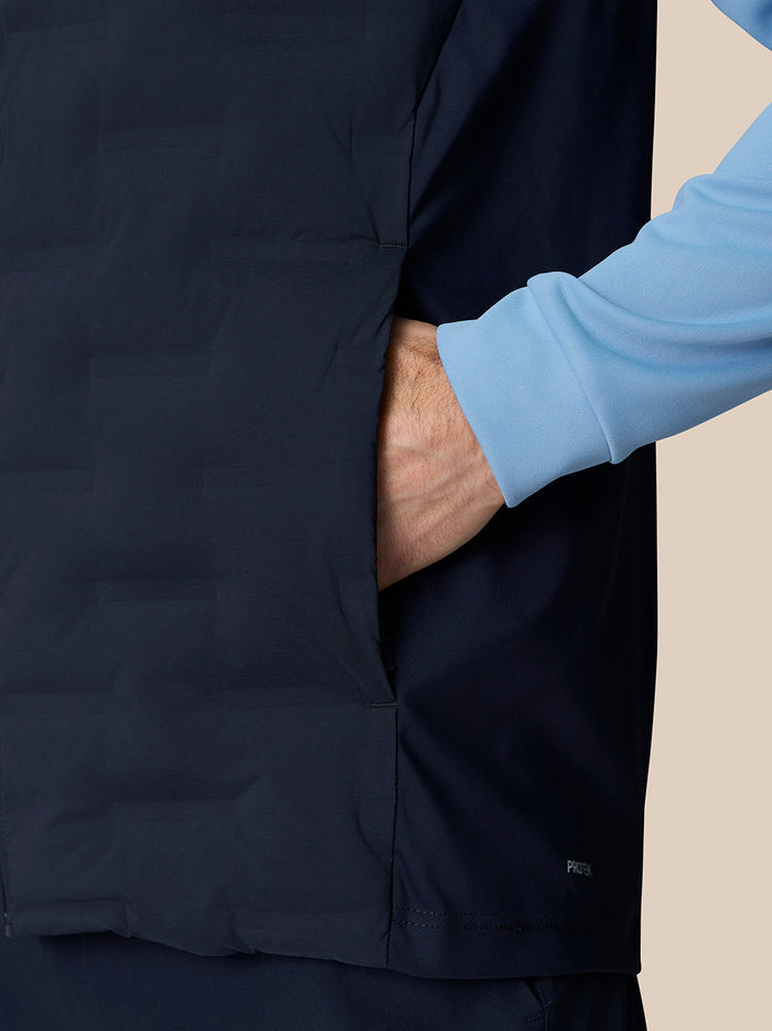 Close up of navy gilet fabric with Protek branding near hem and a light blue sleeve visible