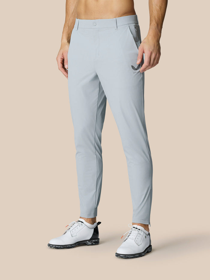 Man wearing light grey Golf Pinnacle 32 trousers with Castore logo on the right thigh and zip cuffs