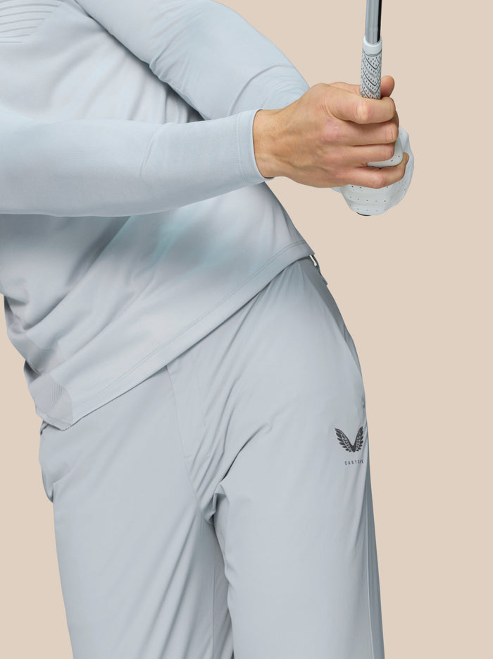 Rear view of male model in light grey golf trousers with Castore branding on the right thigh