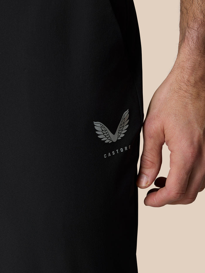 Close-up of black Castore Golf Pinnacle trousers featuring Castore logo on the leg and water droplets on the fabric