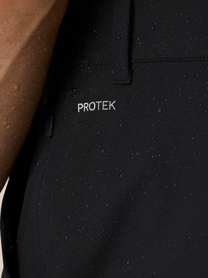 Close-up of ankle area of black Golf Pinnacle trousers with zip hem and pull tab worn with sneakers