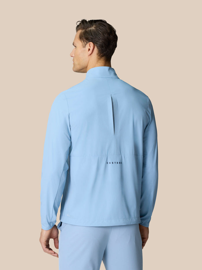 Back view of sky blue Golf Flex Jacket showing center vent and Castore graphic.