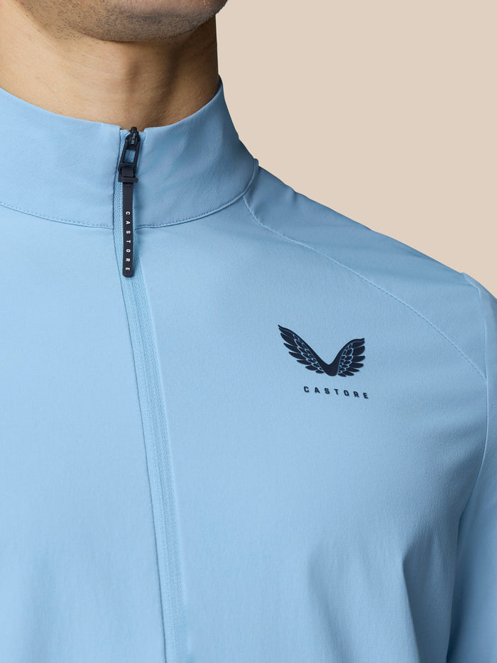 Close-up of sky blue Castore Flex Jacket with front zip and chest logo.