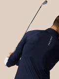 Model wearing Golf Pinnacle Jacket in midnight navy with a golf club resting over the shoulder against a beige background