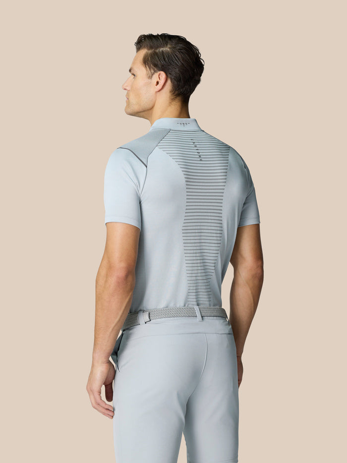 Back view of a man modeling a light grey golf polo with venting panels and mesh back knit