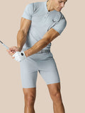 Golfer in a light grey engineered knit polo during a swing, showing fitted silhouette and vented back panels