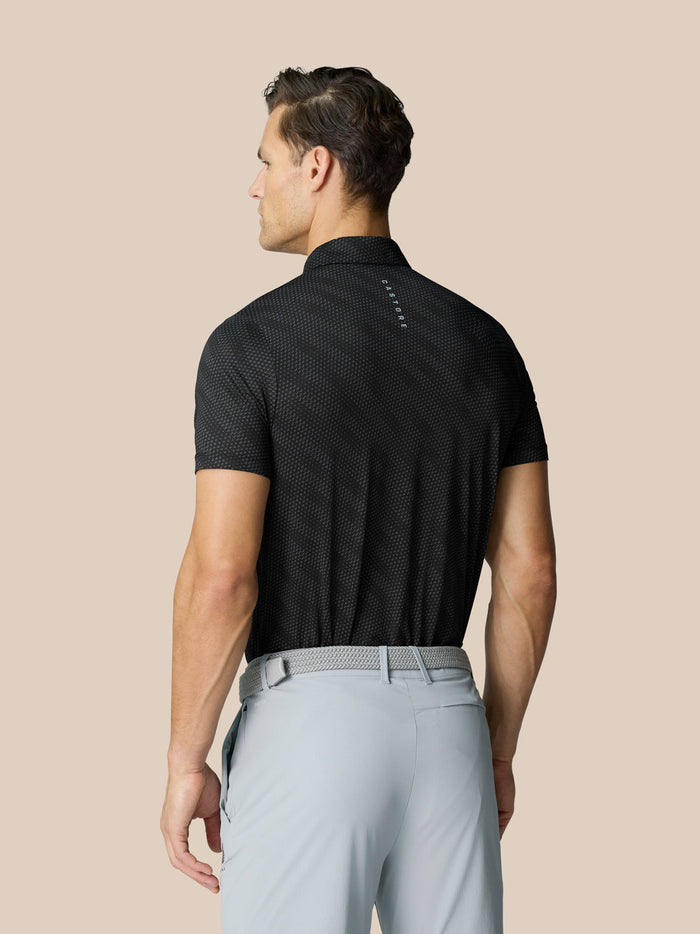Back view of a man wearing black Club Graphic Polo showing a dotted texture and white Castore logo at upper back.
