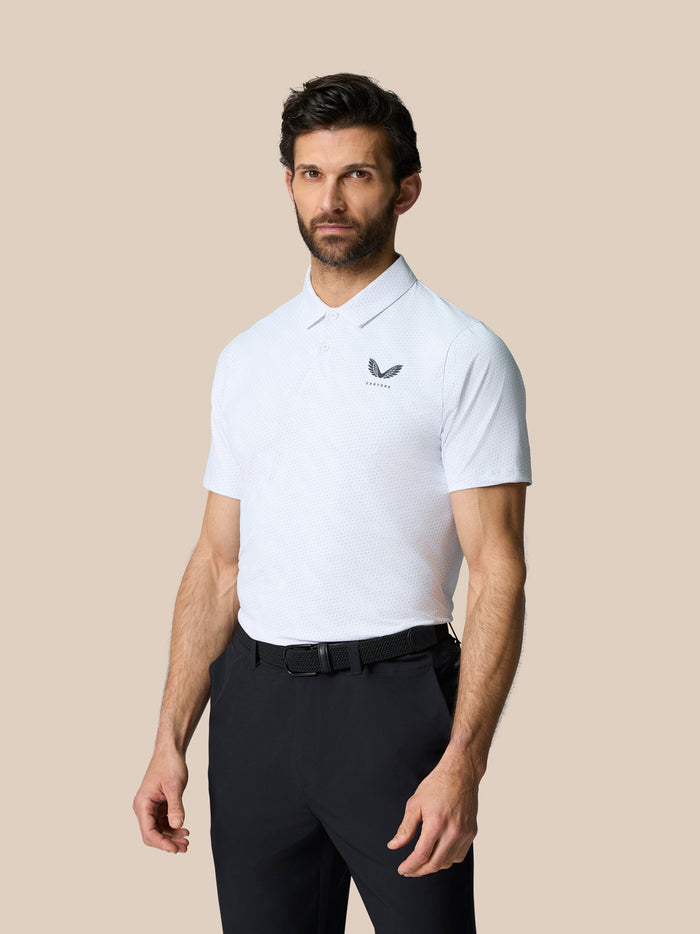 Male model wearing Club Graphic Polo in white with golf ball print all over and Castore branding on the chest.