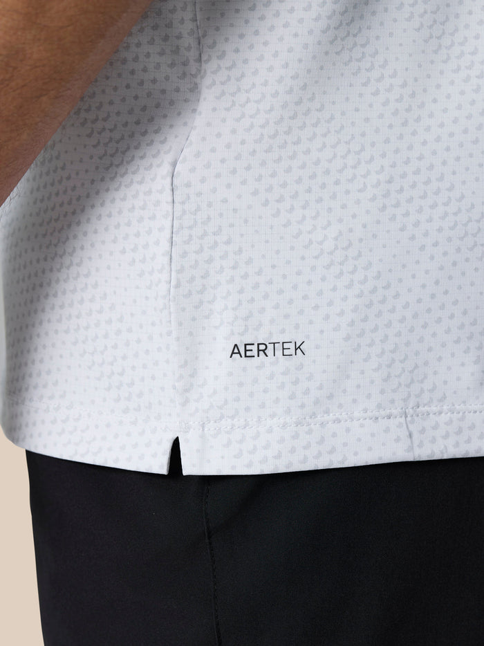 Side view of a white Club Graphic Polo with a small hem slit and AERTEK branding near the hem.