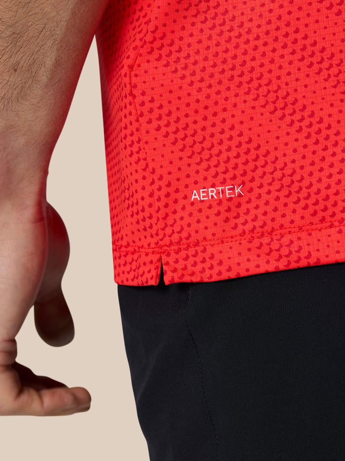 Close up of red polo fabric showing dotted texture and AERTEK branding.