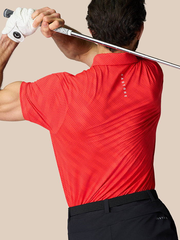 Lower back detail of red polo with AERTEK branding and a hem vent.