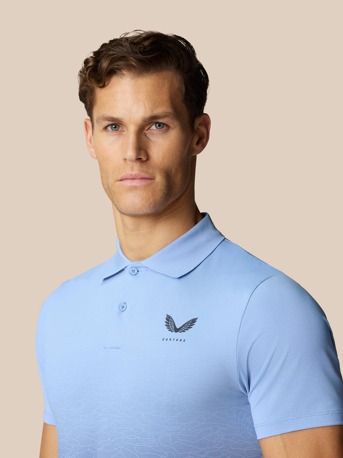 Male model wearing Club Graphic Polo Sky Blue with Castore logo on chest and an ombre pattern on the front.
