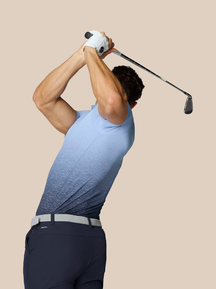 Side view of golfer wearing Sky Blue Club Graphic Polo mid swing with ombre fade from light to dark blue.