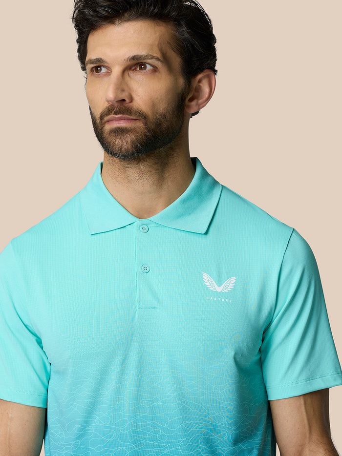 Front view of a man in light aqua Club Graphic Polo with polo collar and Castore logo on chest and gradient pattern.