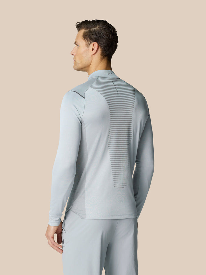 Back view of a man in pale grey Pinnacle LVS quarter zip top with vent panel and logo