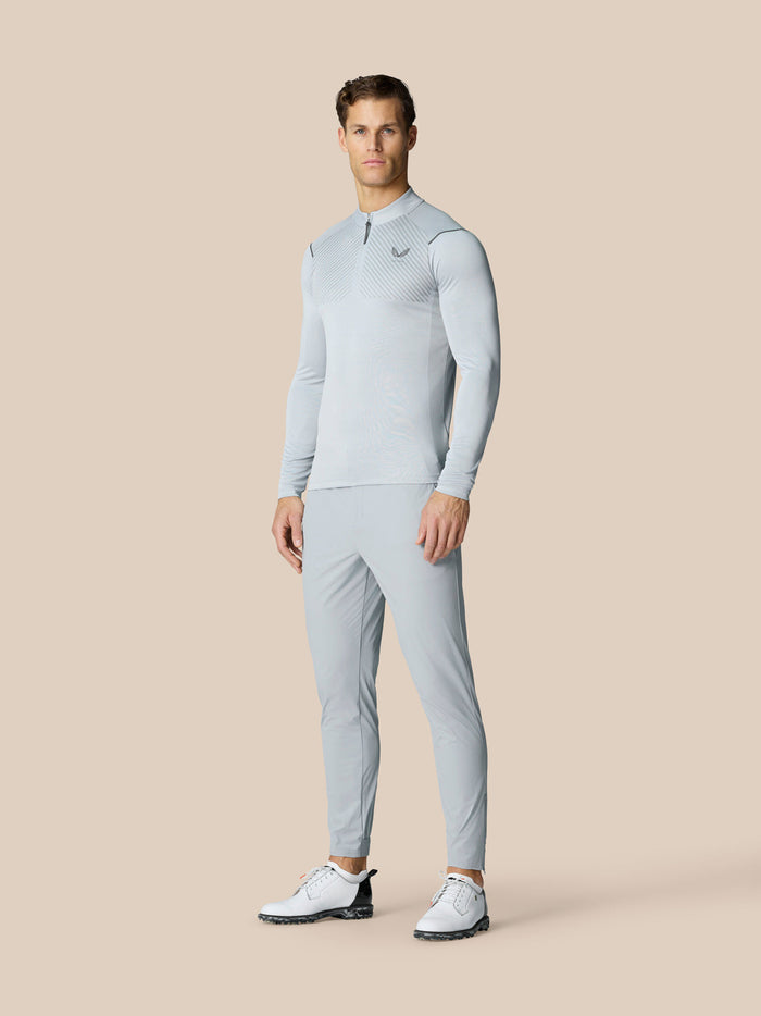 Full body shot of a man in light grey Pinnacle LVS 1/4 Zip Top with matching pants against a beige backdrop