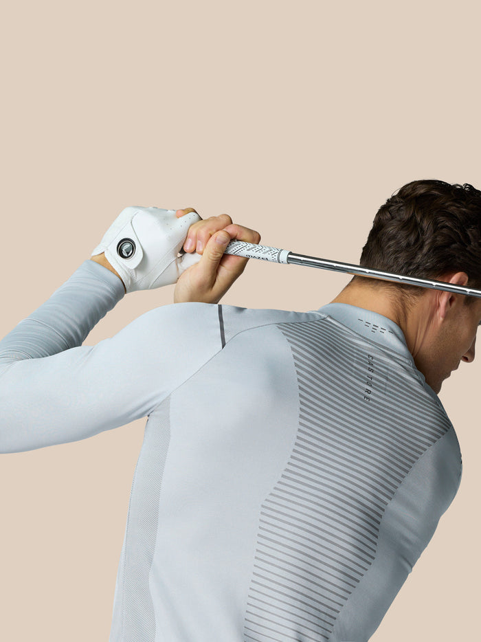 Athlete wearing Pinnacle LVS 1/4 Zip Top in mid grey grips a golf club behind his shoulders