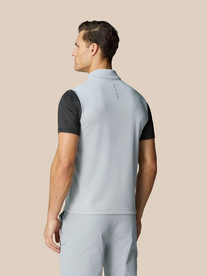 Back view of a light grey sleeveless golf gilet on a male model with Castore branding down the back.