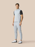 Full body shot of a man in a light grey sleeveless golf gilet with matching pants and white golf shoes